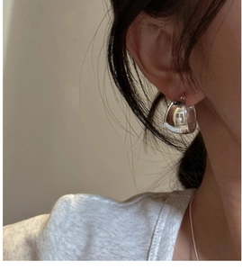 Close-up of polished S925 sterling silver oval hoop earrings on a female model