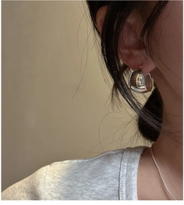 Close-up of minimalist S925 sterling silver oval hoop earrings worn by a model