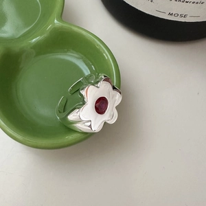 Minimalist S925 sterling silver floral ring with a red zircon on a green ceramic plate