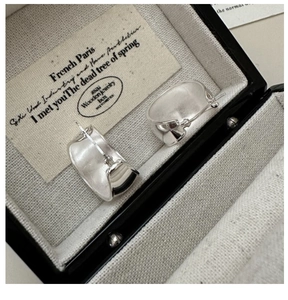 Macro detail of wide-surface silver hoop earrings placed in a premium jewelry box