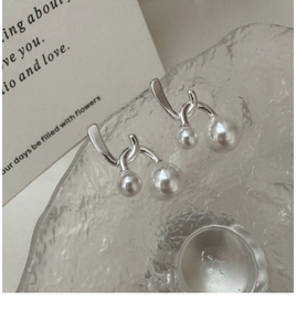 Macro shot of S925 silver cross pearl earrings with glossy metal and white pearls