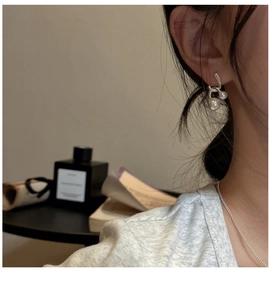 Detail of silver drop earrings with double white pearls worn on a female model