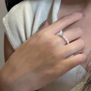 Detail of a silver butterfly pearl ring worn on hand with minimalist aesthetic