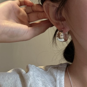 Minimalist S925 sterling silver oval hoop earring shown on model with polished finish
