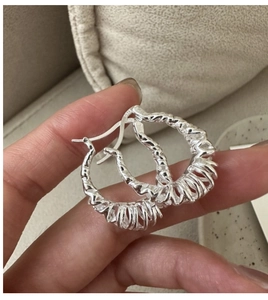 Close-up of S925 sterling silver earrings showing the woven texture and metal hallmark