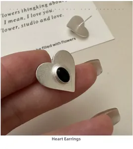 Macro shot of S925 silver heart stud earrings with brushed texture and black onyx stones