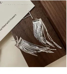 Detailed macro view of S925 sterling silver tassel earrings on a wooden display