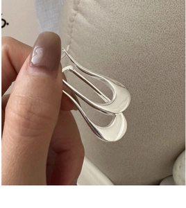 Detail view of polished S925 sterling silver geometric U-shaped earrings with mirror finish