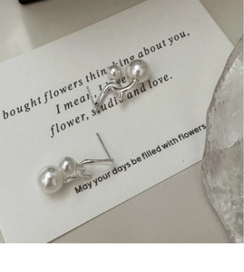 Detail of S925 sterling silver earrings with double white pearls on a wave metal line