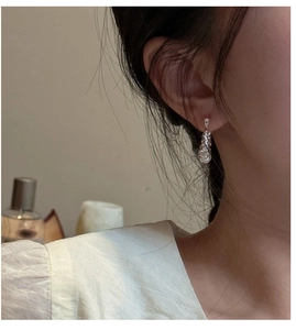 Detail of S925 sterling silver multi-layer knotted earring worn by a model in warm light