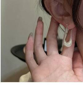 Detail of silver U-shaped hoop earrings showing minimalist polished metal design on ear