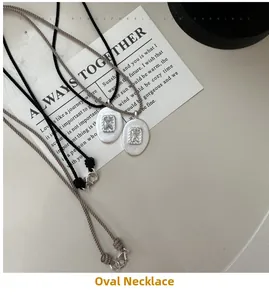 Détail de colliers vintage ovales en argent avec zircon et cordons tressés