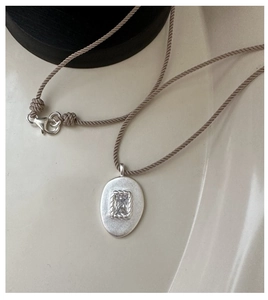 Détail du pendentif ovale en argent S925 mat avec zircon et cordon marron ajusté
