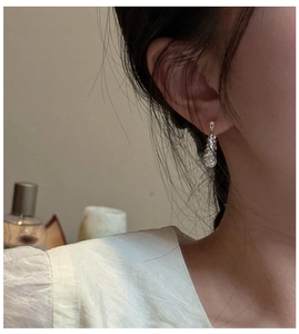 Detailed view of layered silver hoop earrings with textured metal twist design on model