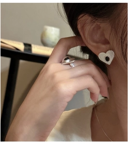 Lifestyle shot of a model wearing minimalist silver heart earrings with black stone inlay