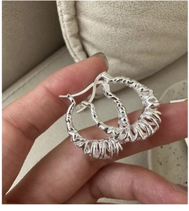 Macro detail of S925 sterling silver stamp on twisted croissant hoop earrings