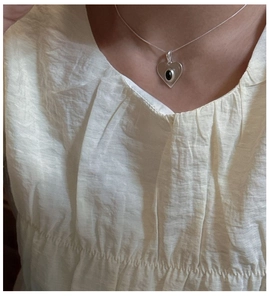 Gros plan d'un pendentif coeur en argent S925 avec gemme noire sur une chaîne fine