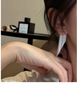Close-up of elegant S925 sterling silver tassel earrings worn by a model in soft lighting