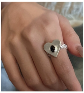 Detail of S925 silver heart ring featuring a black oval gemstone and textured band