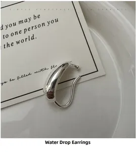 Close-up of polished S925 sterling silver teardrop ear cuff on white ceramic tray
