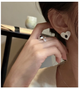 Detail of silver heart-shaped earring and ring set with black stones on a female model