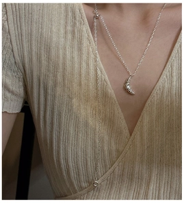 Detail of S925 sterling silver croissant pendant necklace styled on a beige knit sweater