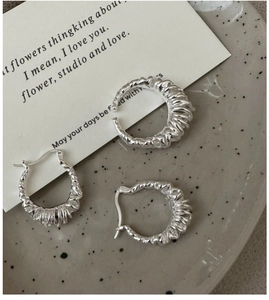 Detail of S925 sterling silver hoop earrings with textured finish on ceramic plate