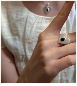 Gros plan d'une bague coeur en argent S925 avec onyx noir sur un doigt féminin