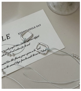 Detail of silver square earrings with hanging metal beads on a minimalist card