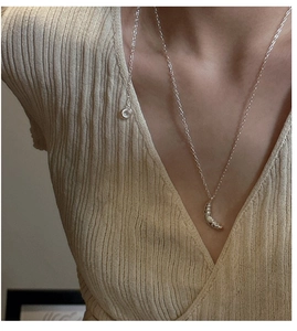 Close-up of minimalist S925 sterling silver croissant pendant on a model's neck