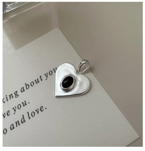 Macro shot of S925 sterling silver heart earrings with matte texture and black stone