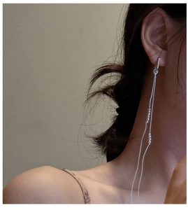 Detail of S925 sterling silver tassel earrings with delicate beads on a model
