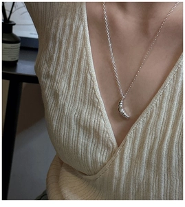 Macro detail of S925 silver croissant necklace on a model showing textured pendant details