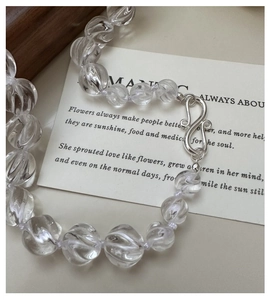 Detailed shot of transparent spiral beads and silver S-hook on a white quote card