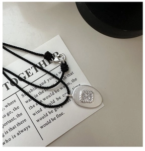 Détail du pendentif en argent S925 mat avec zircon carré et cordon noir tressé