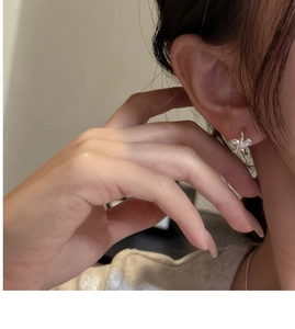 Detailed view of S925 silver bow-knot earring worn on ear with polished mirror finish
