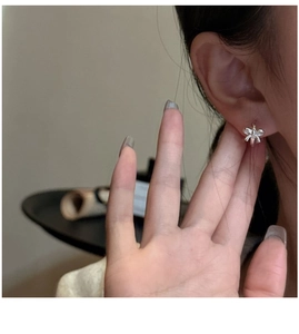Close-up of minimalist S925 sterling silver bow earrings worn on a model's ear