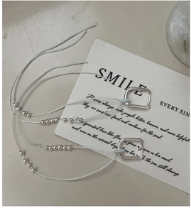 Close-up of S925 sterling silver square hoop earrings with beaded light blue tassels