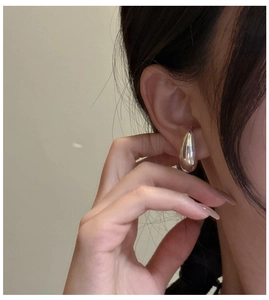 Close-up of polished S925 sterling silver teardrop earrings on a female model
