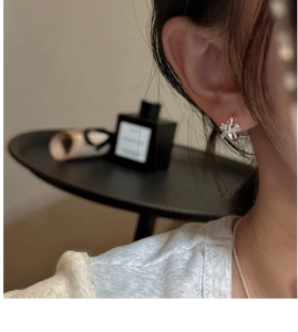 Macro shot of a silver bow earring on ear showing polished finish and sleek minimalist design