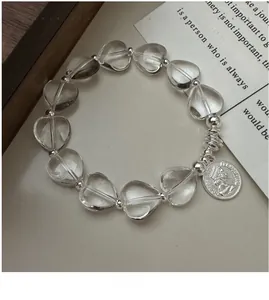 Detail of silver stretch bracelet with clear heart beads and relief queen coin pendant