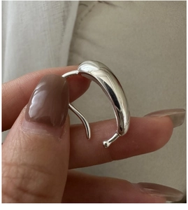 Macro detail of silver teardrop clip-on earring with a polished mirror finish surface