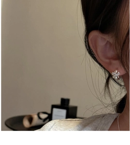 Detail view of silver bow-shaped earring on ear with high-polish mirror finish effect