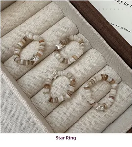 Detailed view of four elastic star rings with neutral mother-of-pearl beads and star pendants