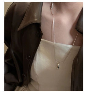 Detail of silver water-drop necklace with sleek snake chain on female model