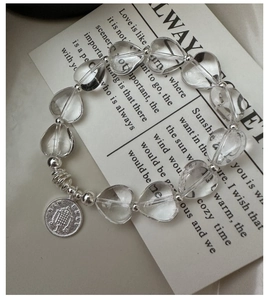 Macro detail of S925 silver heart bracelet with crystal beads and retro coin pendant