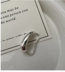 Detailed view of a minimalist S925 sterling silver water drop ear cuff on a white tray