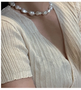 Close-up of S925 silver necklace with baroque pearls on a beige knit sweater