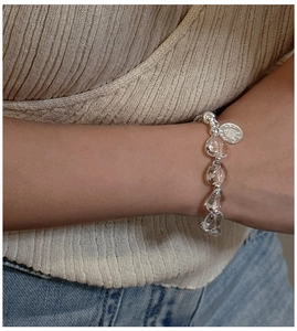Macro detail of beaded silver bracelet with clear crystal drops and round metal charm