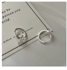 Close-up of S925 sterling silver bow knot hoop earrings on elegant art card background